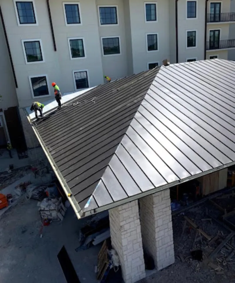 Crew installing standing seam metal roof panels on a commercial project in Lakeside